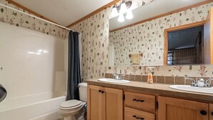 Une salle de bain équipée d’une baignoire, de toilettes et d’un meuble-lavabo avec deux vasques.