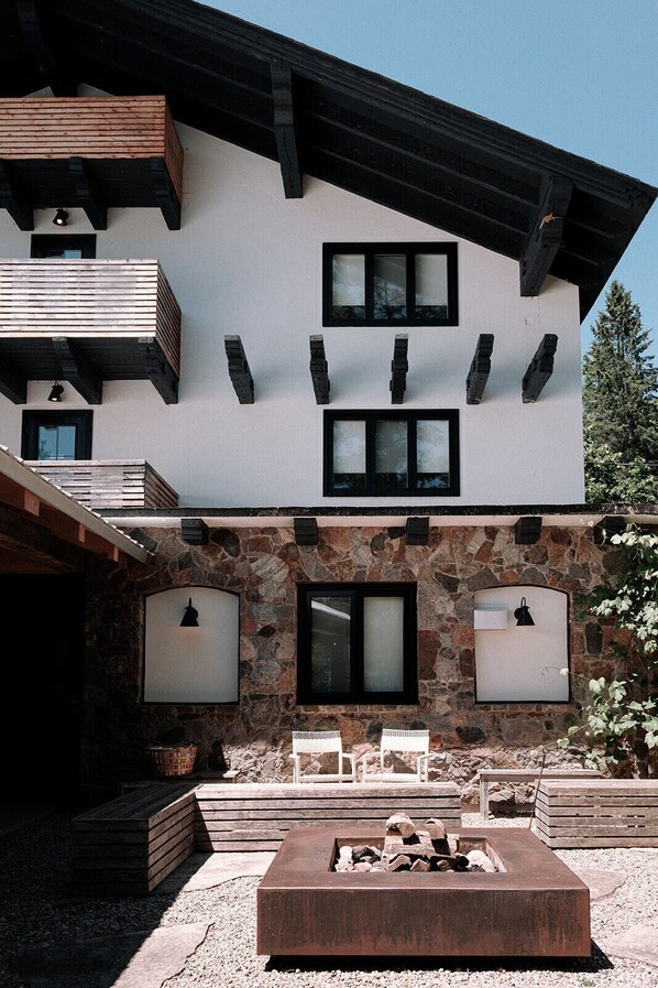 A modern two-story building with a stone facade, multiple windows, and a fire pit in the foreground. - The Wakefield Grand (Wakefield)