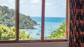 A room with a large window overlooking a coastal area with boats and greenery. - Serenity Hills - Mangonui Holiday Home (Mangonui)