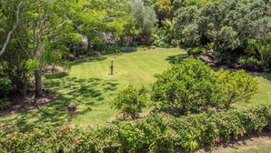 A lush garden with a well-maintained lawn, various shrubs, and trees. - Serenity Hills - Mangonui Holiday Home (Mangonui)