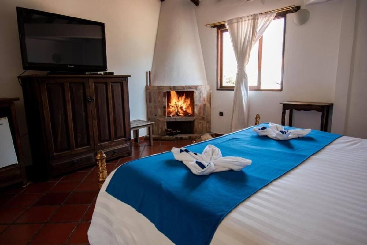 Ein Hotelzimmer mit Bett, Fernseher, Kamin und einem Fenster mit Vorhängen.