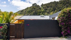Un bâtiment moderne à l’extérieur noir, doté d’un portail en bois et portant le numéro « 13B ».