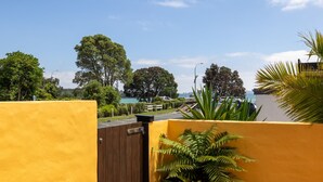 Un mur jaune avec une porte en bois, un parking et une vue sur des arbres et une étendue d’eau.