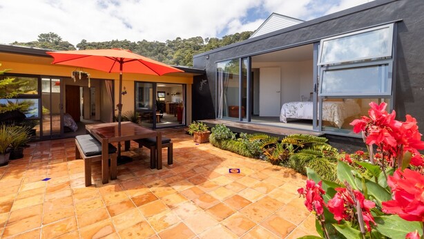 Une maison moderne dotée d’un patio, d’un coin repas et d’une grande porte-fenêtre coulissante donnant accès à une chambre.