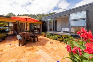 A modern house with a patio, a dining area, and a large sliding glass door leading to a bedroom.