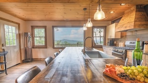 Una cocina amplia con una larga mesa de madera, un horno empotrado y vistas al exterior.
