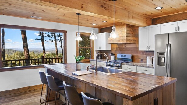 Una cocina moderna con una isla grande, electrodomésticos de acero inoxidable y vistas al exterior.