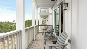 Eine überdachte Veranda mit Holzgeländern, einem Deckenventilator und zwei Adirondack-Stühlen.