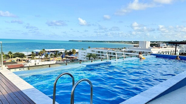 Piscina con vistas al mar y edificios al fondo.
