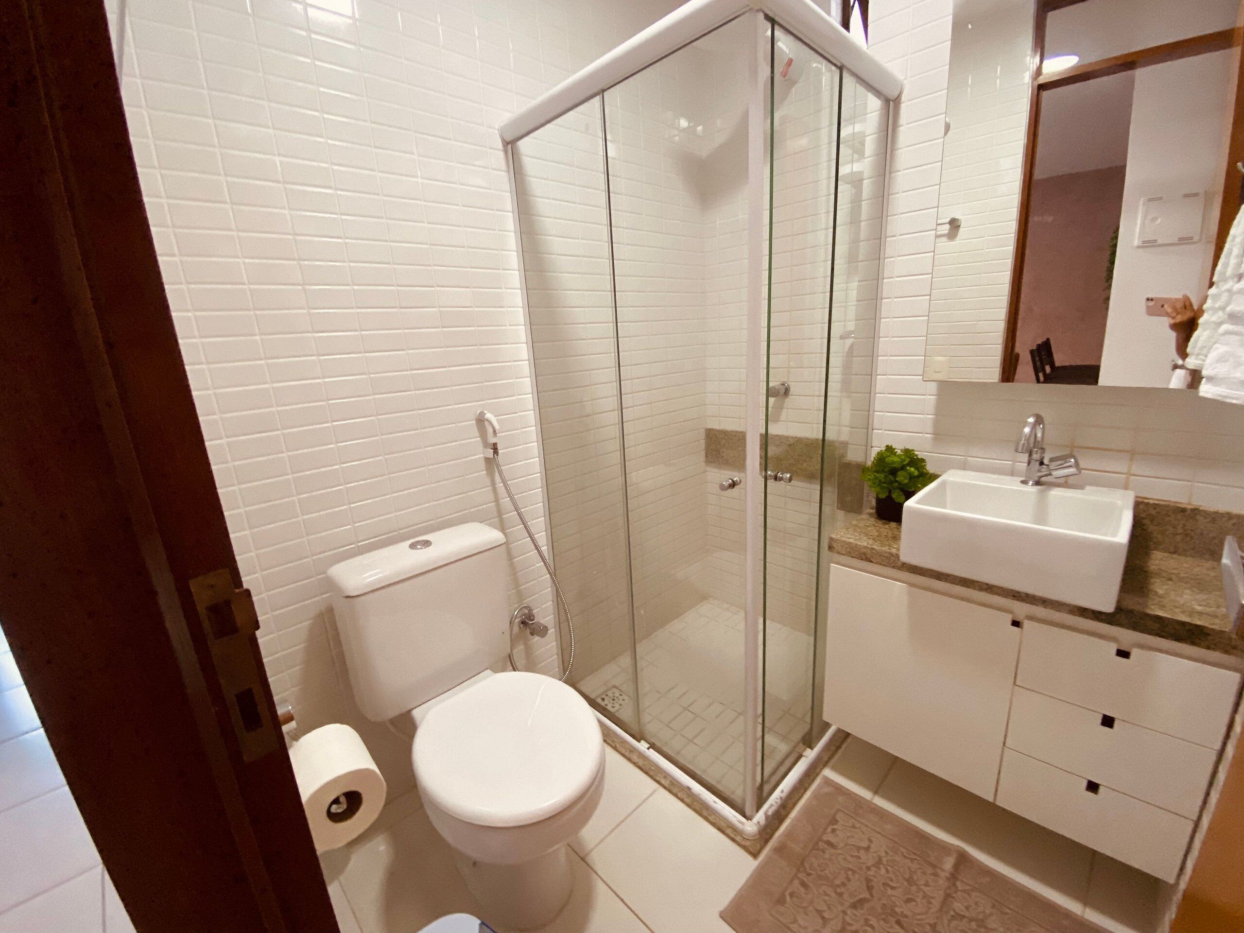 A bathroom with a glass-enclosed shower, a toilet, a sink, and a mirror.