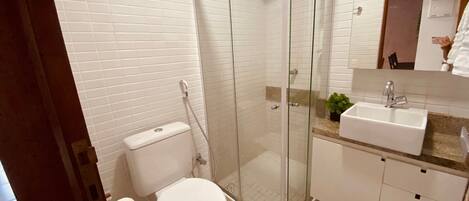 A bathroom with a glass-enclosed shower, a toilet, a sink, and a mirror.