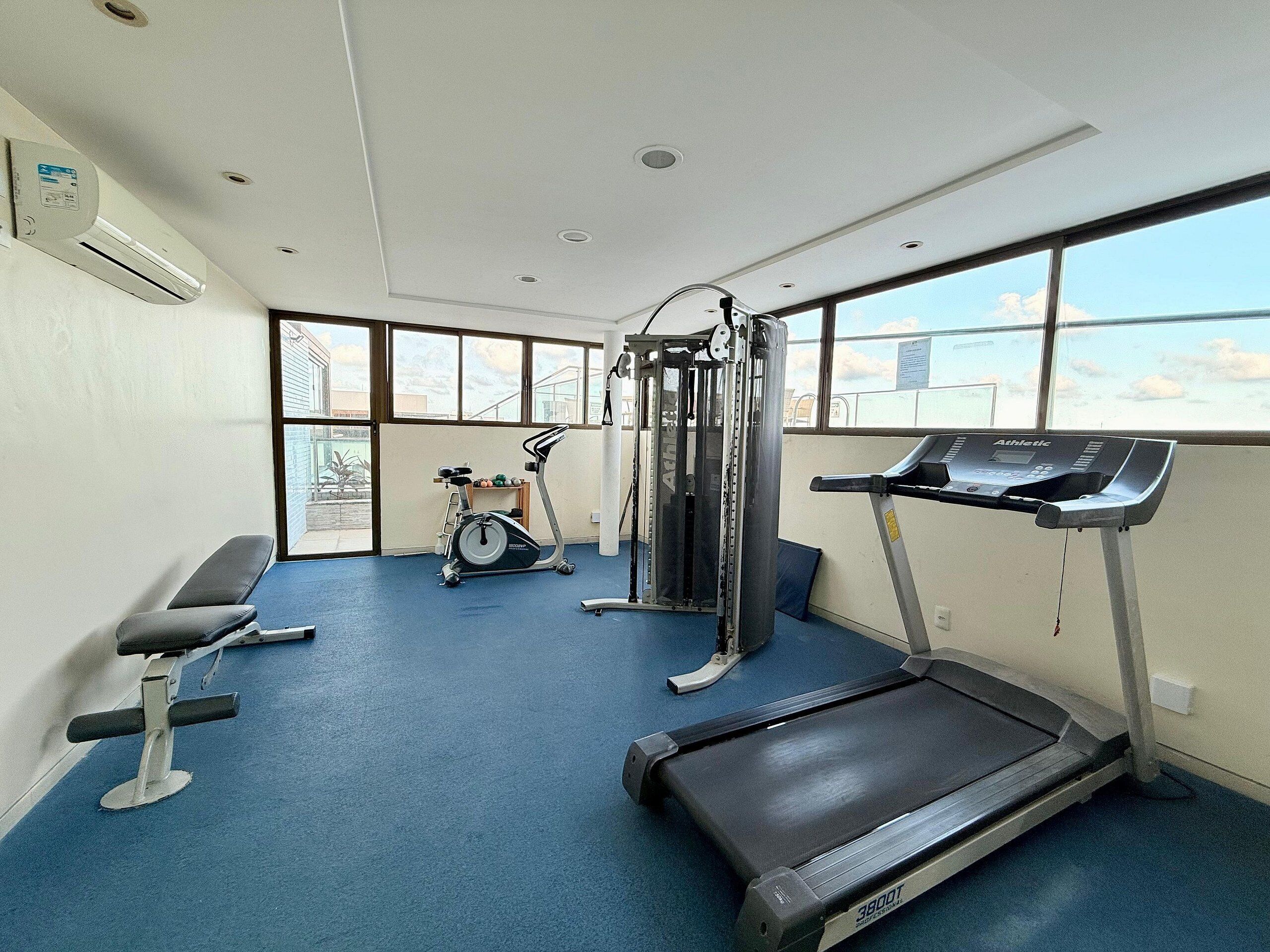 A gym with a treadmill, weight machine, and bench.