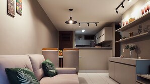 Una sala de estar moderna con un sofá, una mesita con un frutero, y una cocina al fondo.
