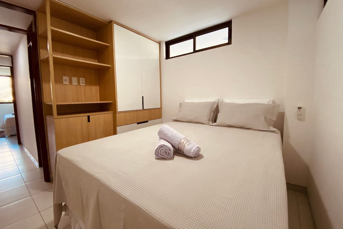 A bedroom with a bed, a wardrobe, and a small window.