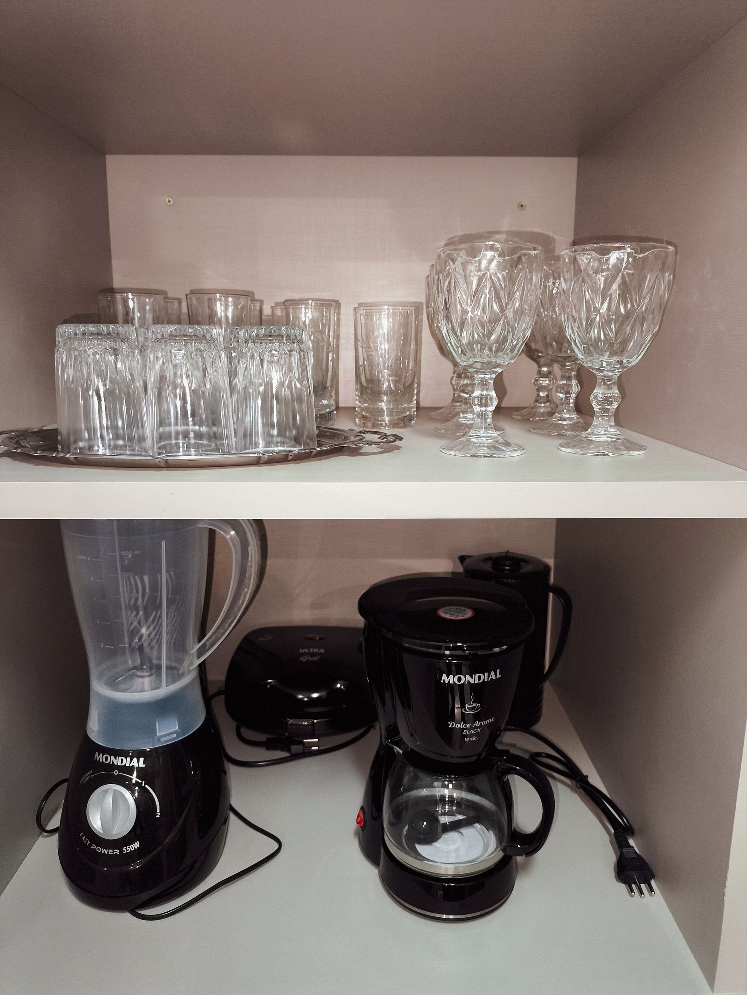 Ein Küchenregal mit verschiedenen Gläsern und einer Kaffeemaschine.