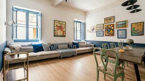 Ein Wohnzimmer mit einer Couch, einem Esstisch, Stühlen und Kunstwerken an den Wänden.