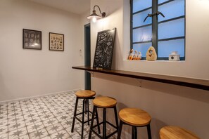 Ein Zimmer mit Fliesenboden, einer Bar mit Hockern, einer Tafel mit Schrift und einem Fenster mit Blick.