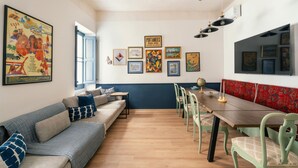 Ein Zimmer mit einer Couch, einem Esstisch, Stühlen und Wandbildern.