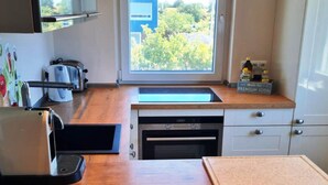 A modern kitchen with a wooden countertop, a built-in oven, a dishwasher, and a window with a view of greenery. - Haus am Merr auf Fehmarn OT Westerbergen (Fehmarn)