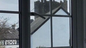 A window with a view of a building with a pointed roof and a chimney.