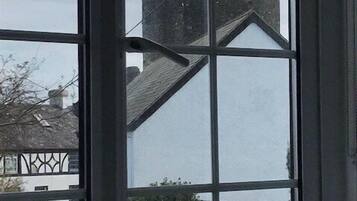 A window with a view of a building with a pointed roof and a chimney.