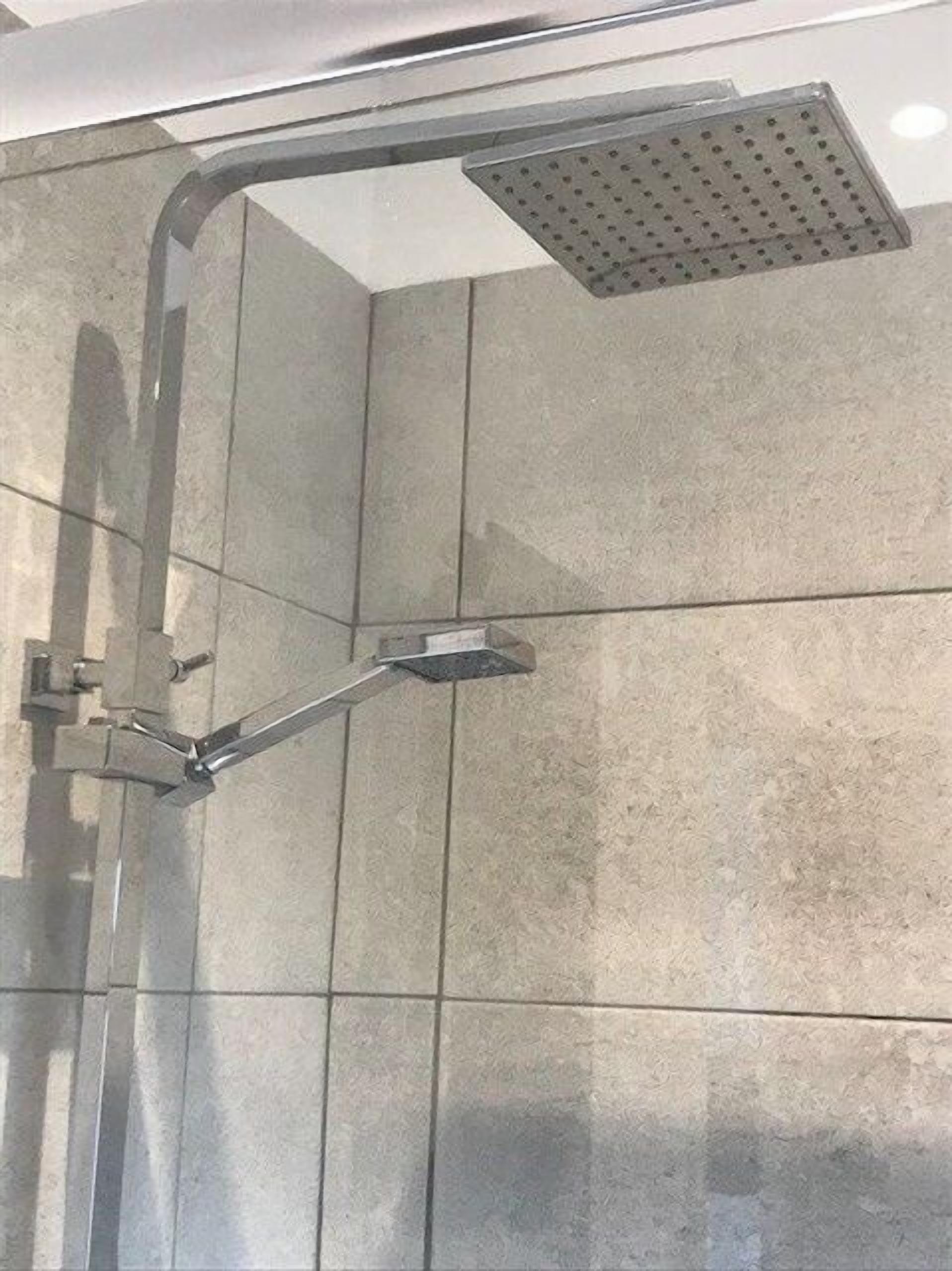 Eine Dusche mit Duschkopf und Regendusche.