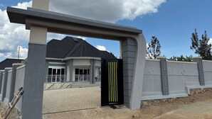 Una entrada protegida con un diseño arquitectónico moderno, que presenta un arco de hormigón y una verja de metal.