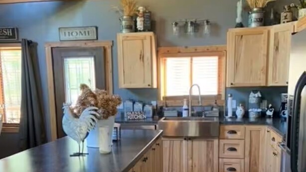 Una cocina con gabinetes de madera, un lavamanos de acero inoxidable y un refrigerador.