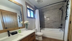 Une salle de bain avec un meuble-lavabo en bois, un lavabo blanc, des toilettes et une baignoire.