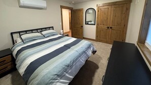 Une chambre à coucher avec un lit, une commode, un miroir et une armoire.