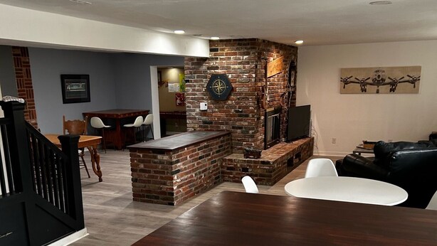 Una cocina moderna con encimera de madera oscura, armarios blancos y una pared decorativa de ladrillo.