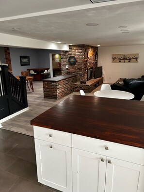 Una cocina moderna con encimera de madera oscura, armarios blancos y una pared decorativa de ladrillo.