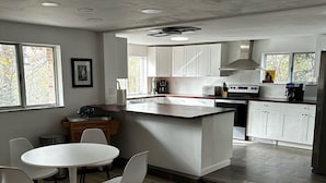 Una cocina moderna con armarios blancos, una isla central y un comedor con una mesa redonda y sillas.