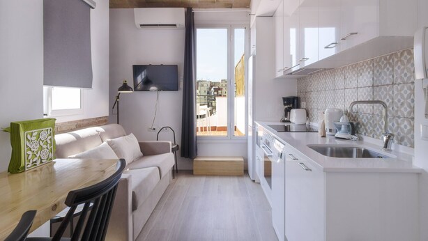 A compact living space with a kitchenette, a dining area, and a sofa. - OLA LIVING CALID ATTIC (Hospitalet de Llobregat)