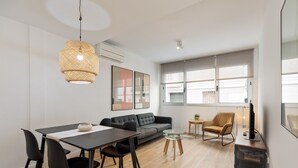 Een moderne woonkamer met een eethoek, een bank, een salontafel en een tv-meubel.