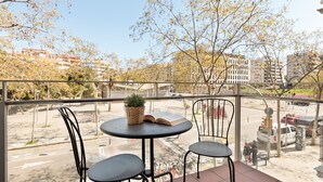 A balcony with two chairs and a table, a potted plant, and a book.