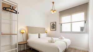A bedroom with a bed, bedside tables, a wardrobe, and a window with a view.