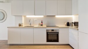 Eine moderne Küche mit weißen Schränken, einem eingebauten Geschirrspüler und einem Edelstahlbackofen.