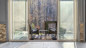 A sliding glass door leading to an outdoor patio with two rocking chairs and a small table. - Private Pool! Newly built! Convenient location! (Sevierville)