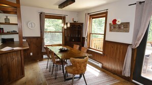 Een houten eethoek met een glazen tafel, stoelen en een klok aan de muur.