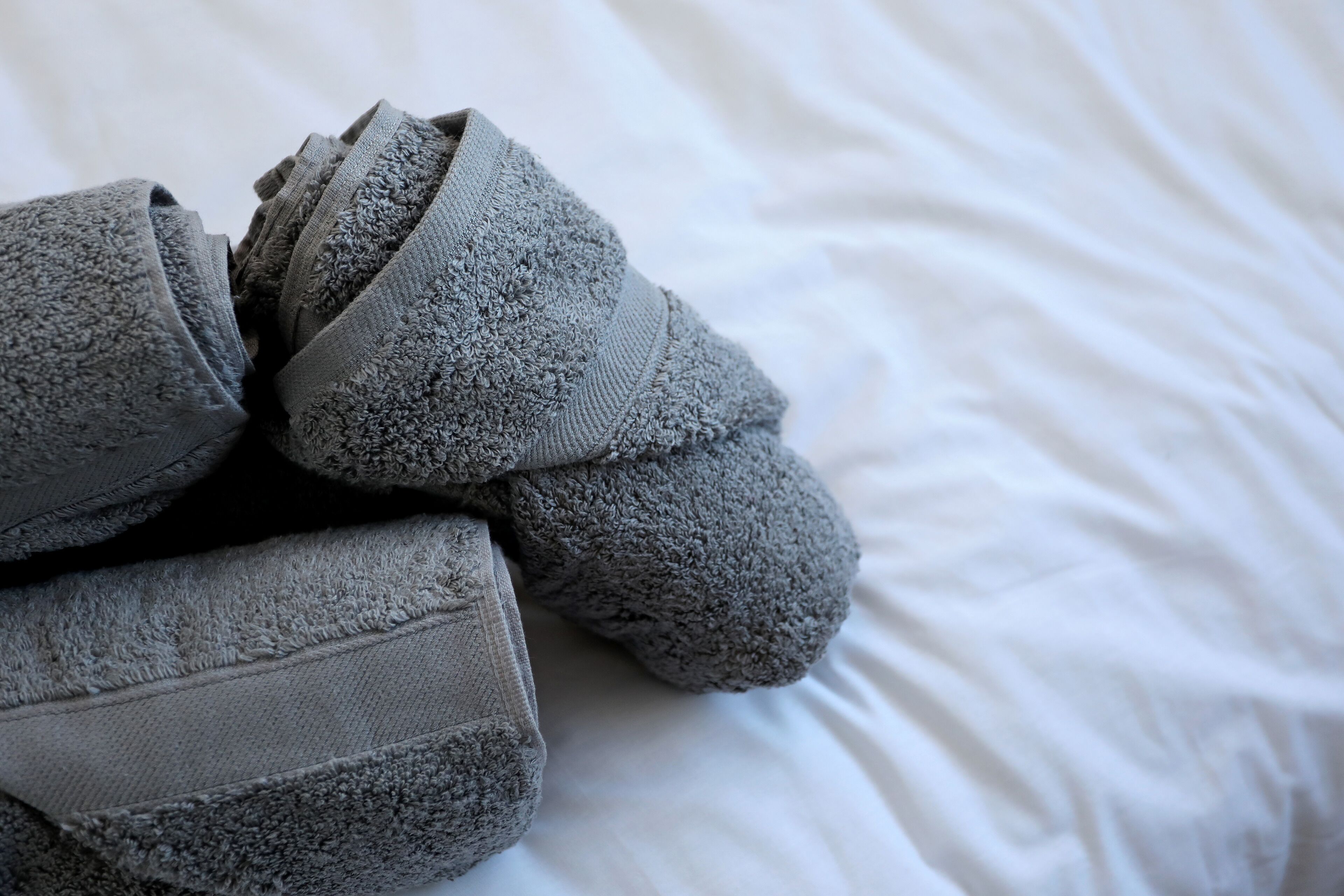 Grijze pantoffels op een wit bed.