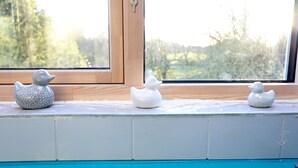A window sill with three ceramic ducks and a view of trees outside. - Picturesque Family Hideaway Chipping Ongar Essex (Ongar)