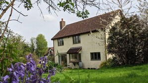 A two-story house with a sloped roof, a chimney, and a front porch. - Picturesque Family Hideaway Chipping Ongar Essex (Ongar)