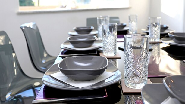 A dining table set with plates, bowls, and clear glasses, with chairs on either side. - Picturesque Family Hideaway Chipping Ongar Essex (Ongar)