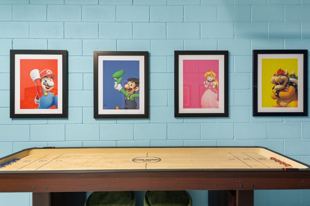 A room with a pool table and four framed pictures on the wall.