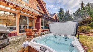A hot tub in a backyard with a wooden deck, a barbecue grill, and a patio table with chairs. - 3BD/3BA Village Townhome/Hot Tub (Whistler)