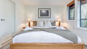 A neatly made bed with white linens and a gray blanket, two bedside lamps, and a framed picture on the wall. - 3BD/3BA Village Townhome/Hot Tub (Whistler)