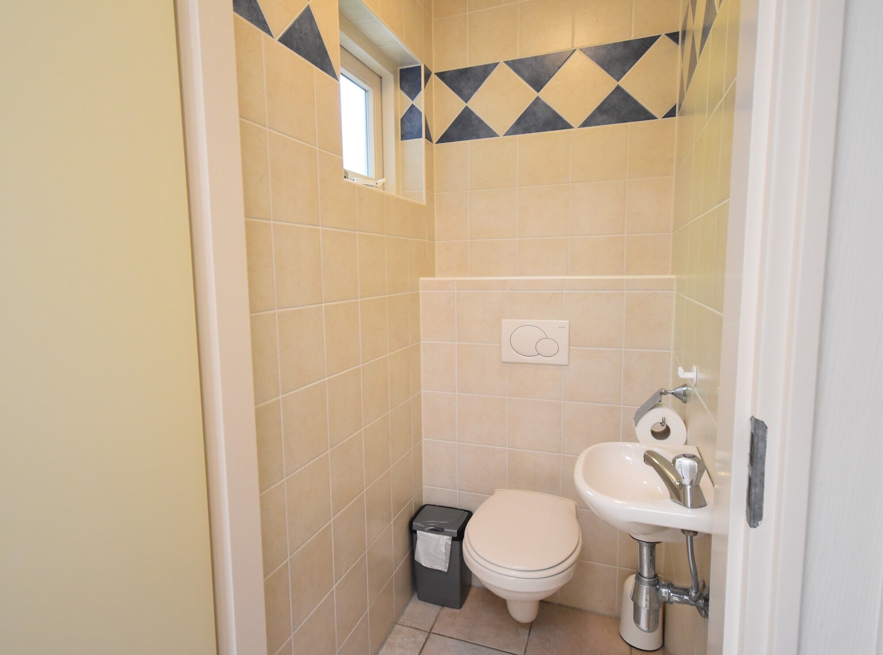 Un baño pequeño y funcional con inodoro, lavamanos y cubo de basura.
