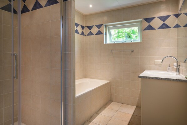 Un baño con ducha, bañera y lavamanos.
