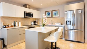 A modern kitchen with a central island, stainless steel appliances, and a white color scheme.